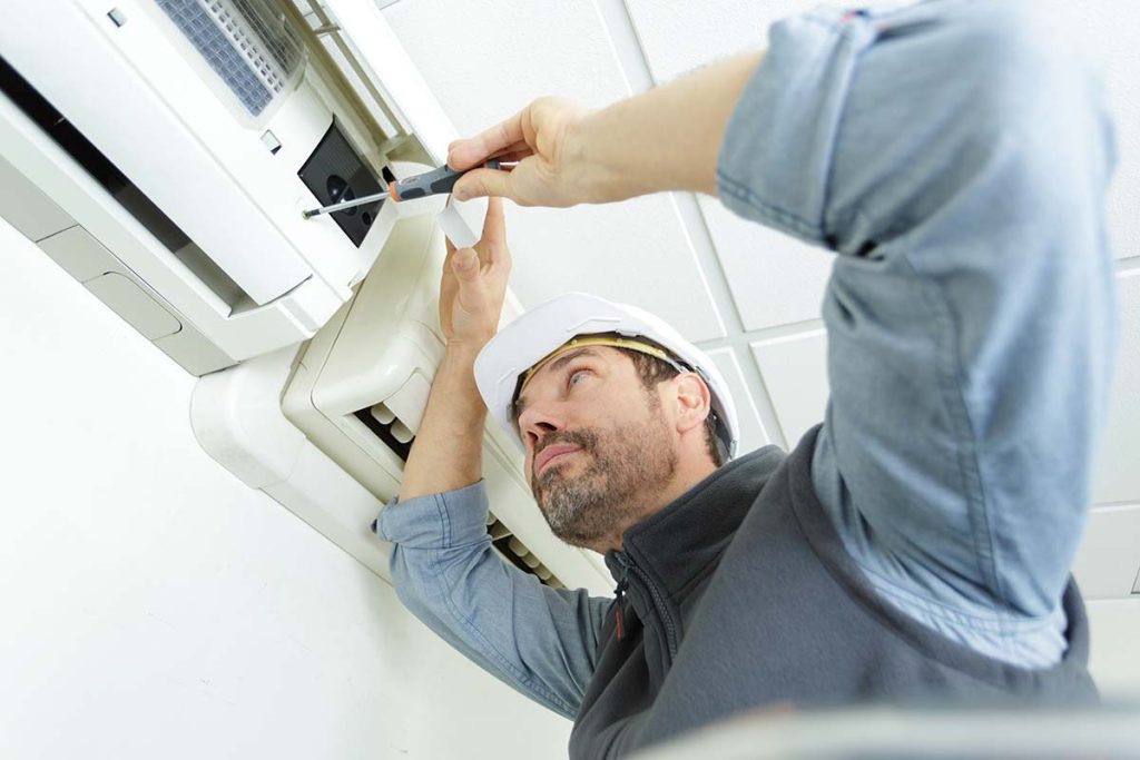 A skilled technician from Lund Plumbing and Heating is meticulously servicing an air conditioning unit, ensuring residents of Cambridge, Massachusetts, can enjoy a cool and comfortable home environment.