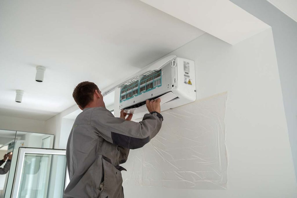 Technician servicing an air conditioning unit, ensuring efficient cooling services by Lund Plumbing and Heating in Wakefield, Massachusetts