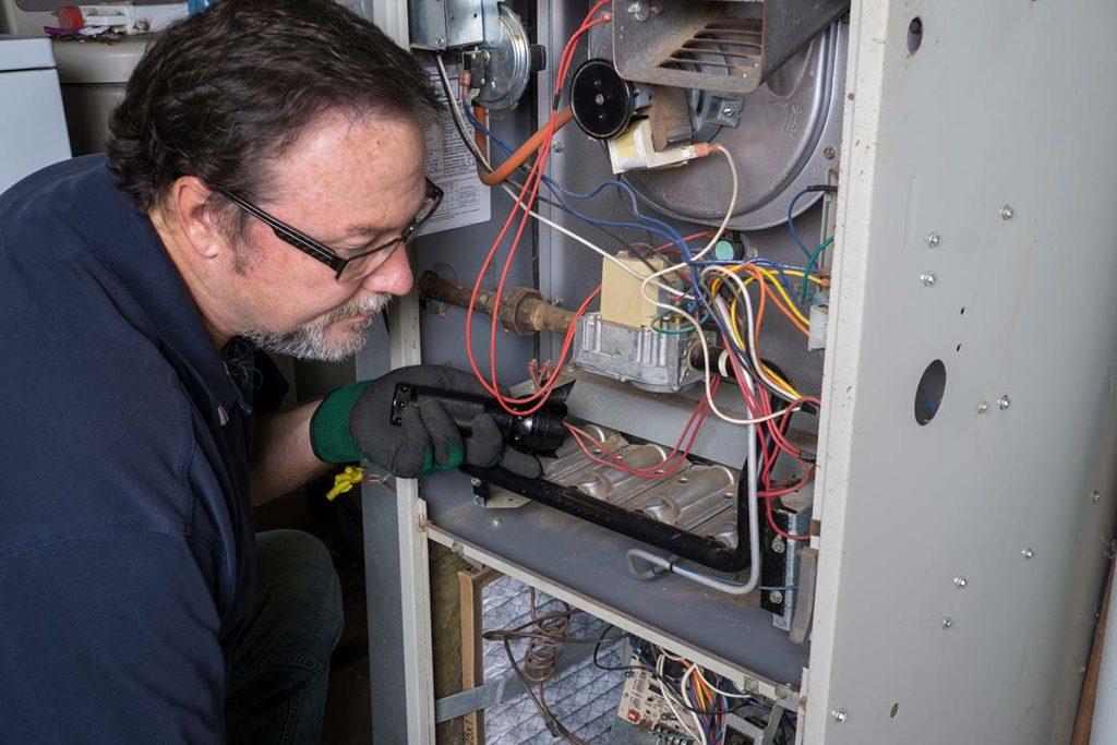 A focused technician servicing a furnace, representing the detailed and expert heating services provided by Lund Plumbing and Heating in Lexington, Massachusetts.