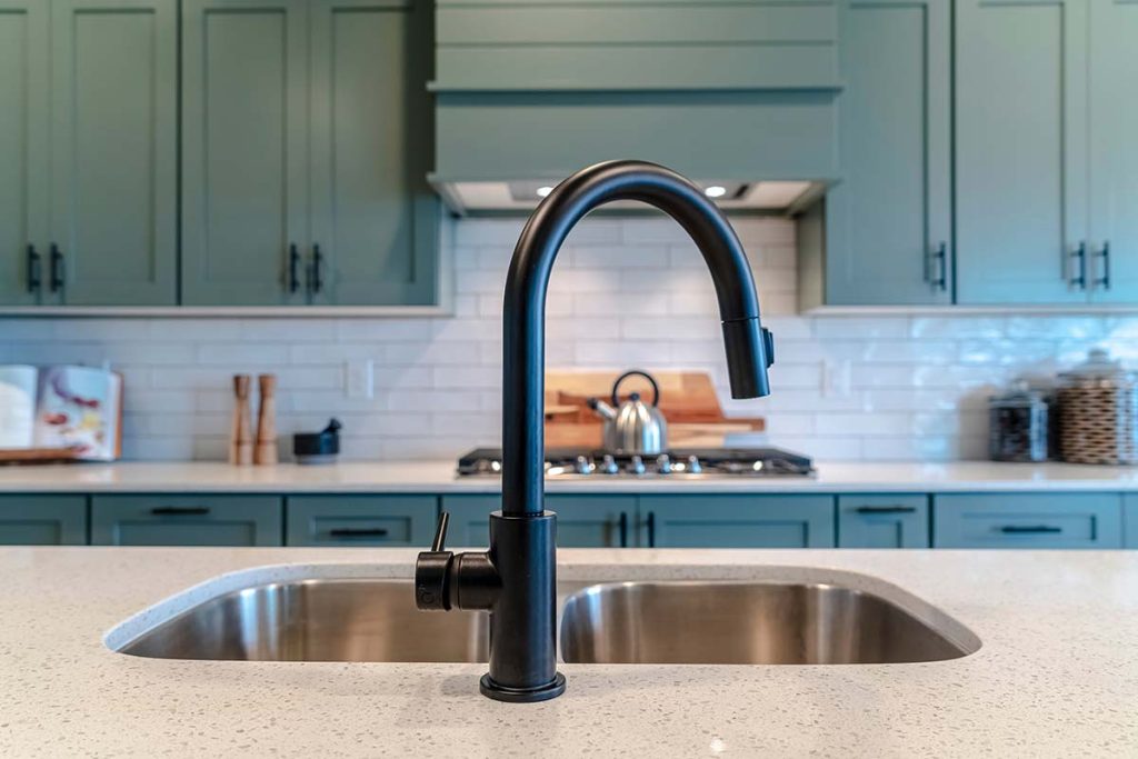 Sleek black kitchen faucet over a stainless steel sink, showcasing the modern plumbing installations by Lund Plumbing and Heating in Arlington, Massachusetts.