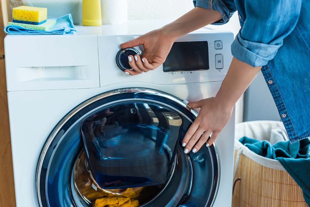 A woman loading a washing machine, reflecting the essential plumbing services for everyday appliances by Lund Plumbing and Heating in Melrose, Massachusetts.