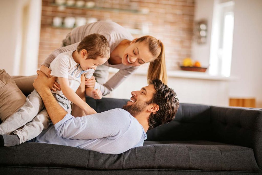 Happy family enjoying time together on a couch, symbolizing the satisfaction of Lund Plumbing and Heating's customers in Belmont, Massachusetts.