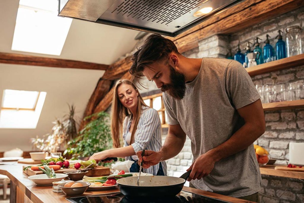 A couple preparing a meal together in a rustic kitchen, capturing the satisfaction customers feel with Lund Plumbing and Heating's services in Malden, Massachusetts.