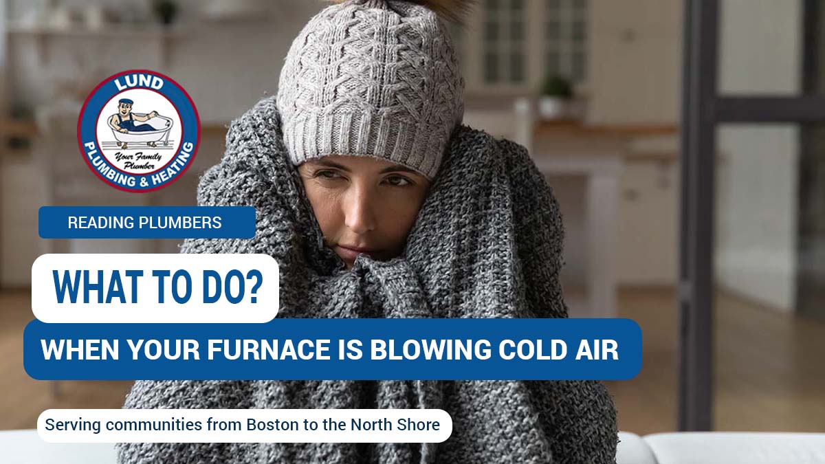 A woman bundled in a blanket indoors, illustrating the discomfort caused by a furnace blowing cold air in winter.